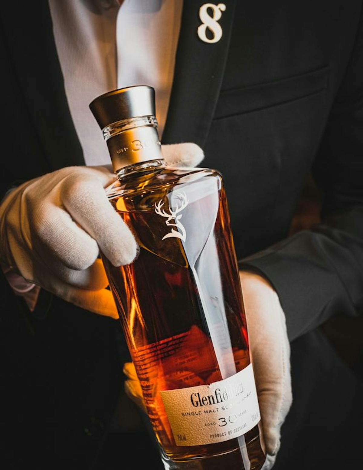 a close up of a person holding a bottle of glenfiddich