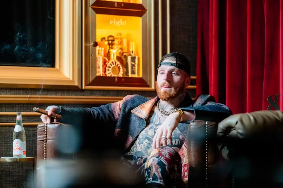 Maxx Crosby sitting in front of a curtain