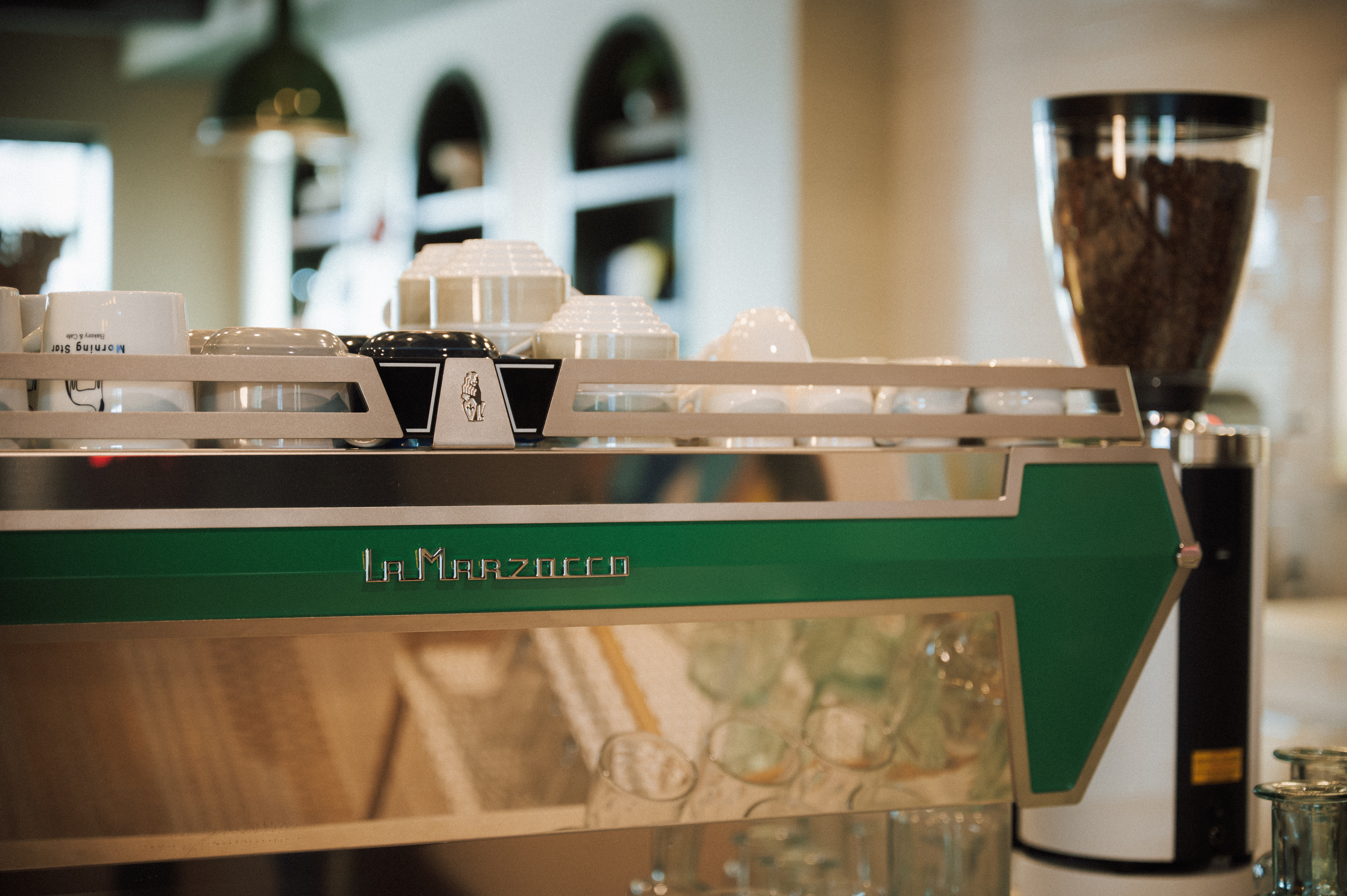 a coffee machine with a green arrow and white cups
