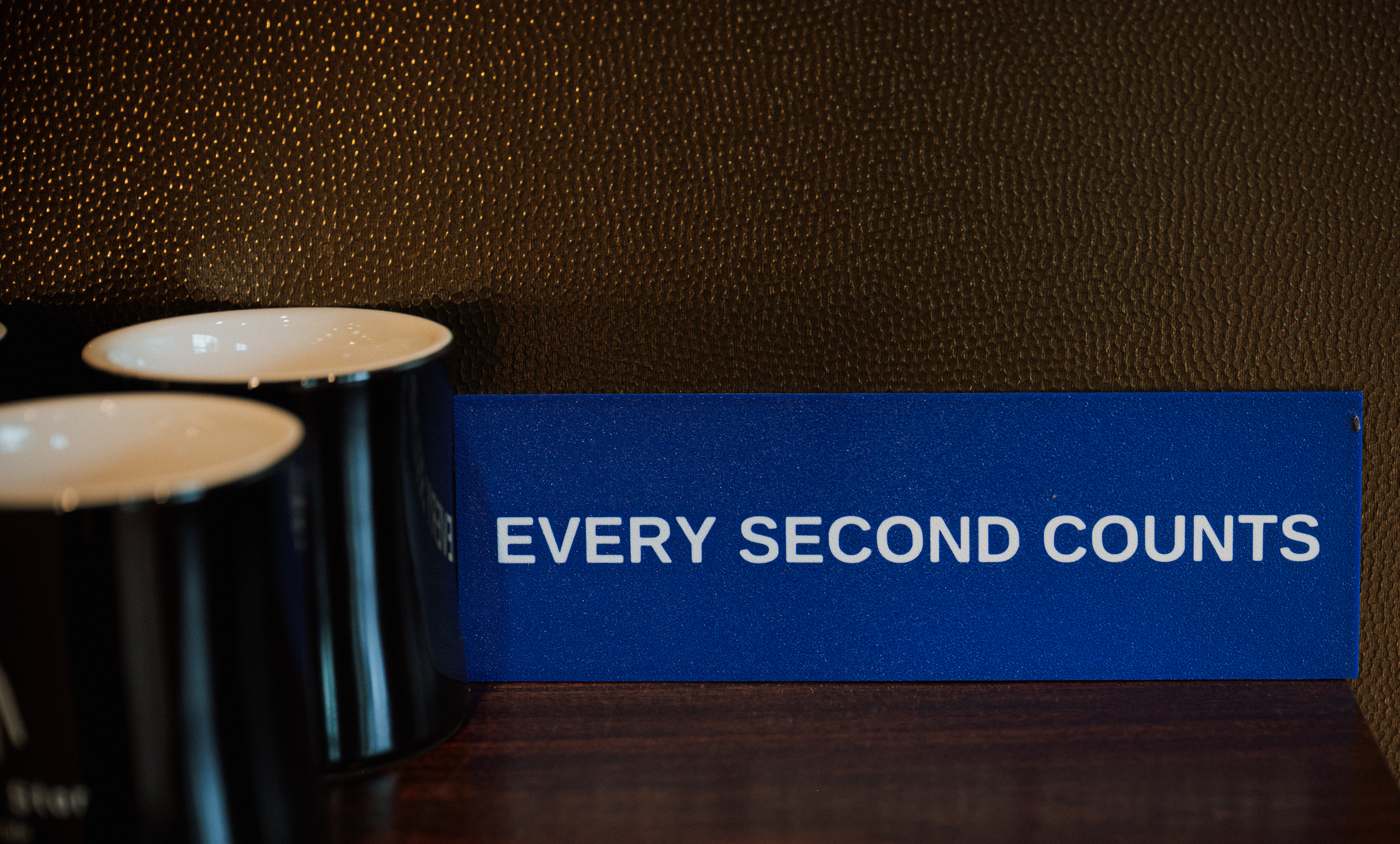 a blue sign with white text on it next to two black mugs