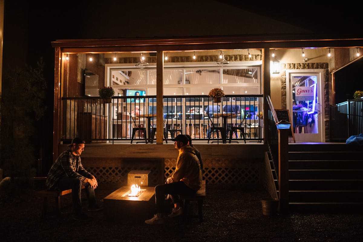 a group of people sitting in front of a building lit up at night