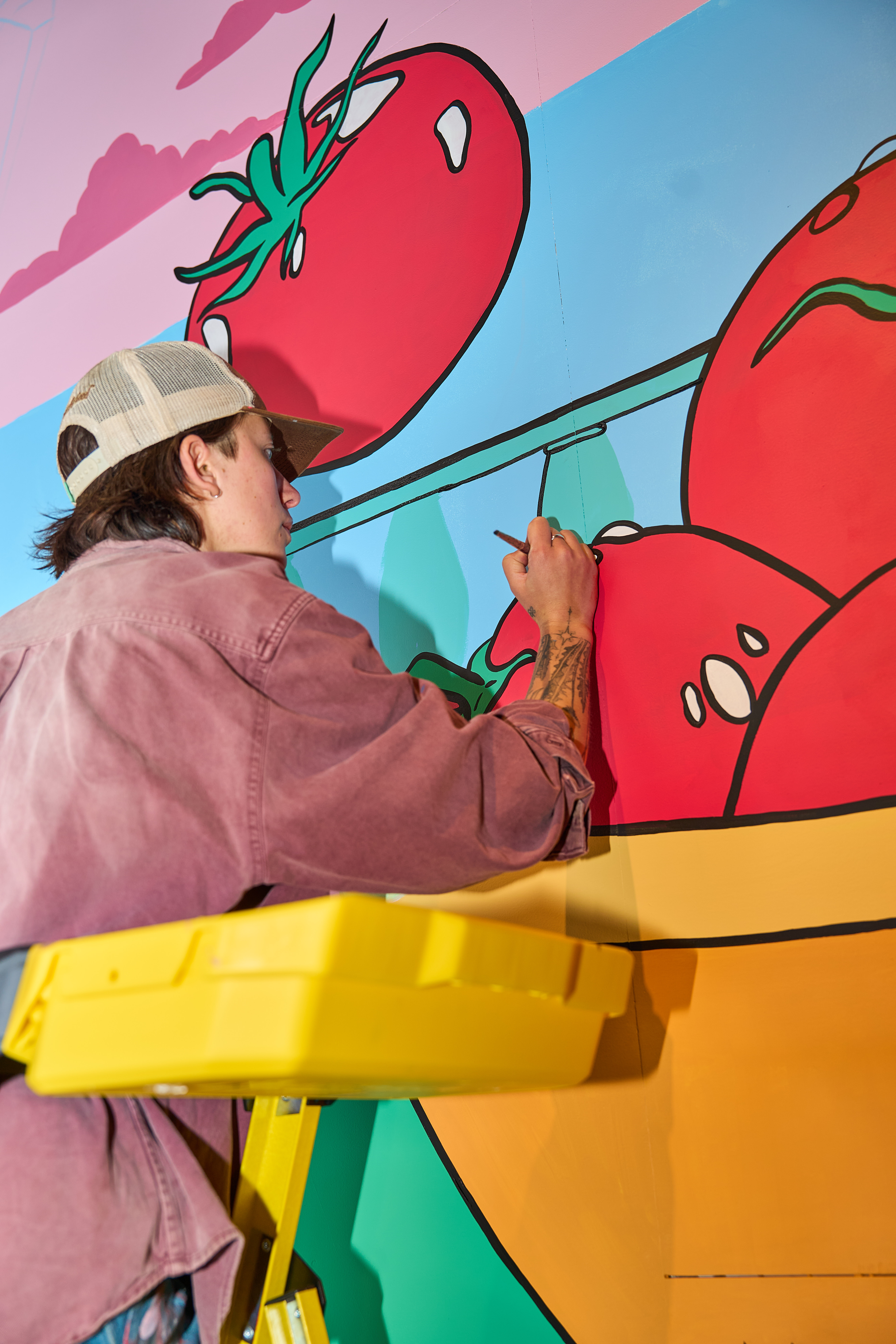 artist painting a mural at Naya Williamsburg location