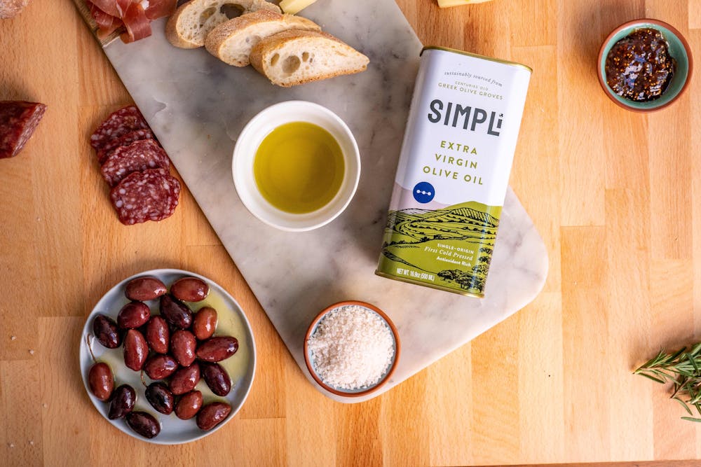 SIMPLi food products pictured: olives, olive oil, salt in frame with bread and meats. SIMPLi's Kalamata olives at Naya 