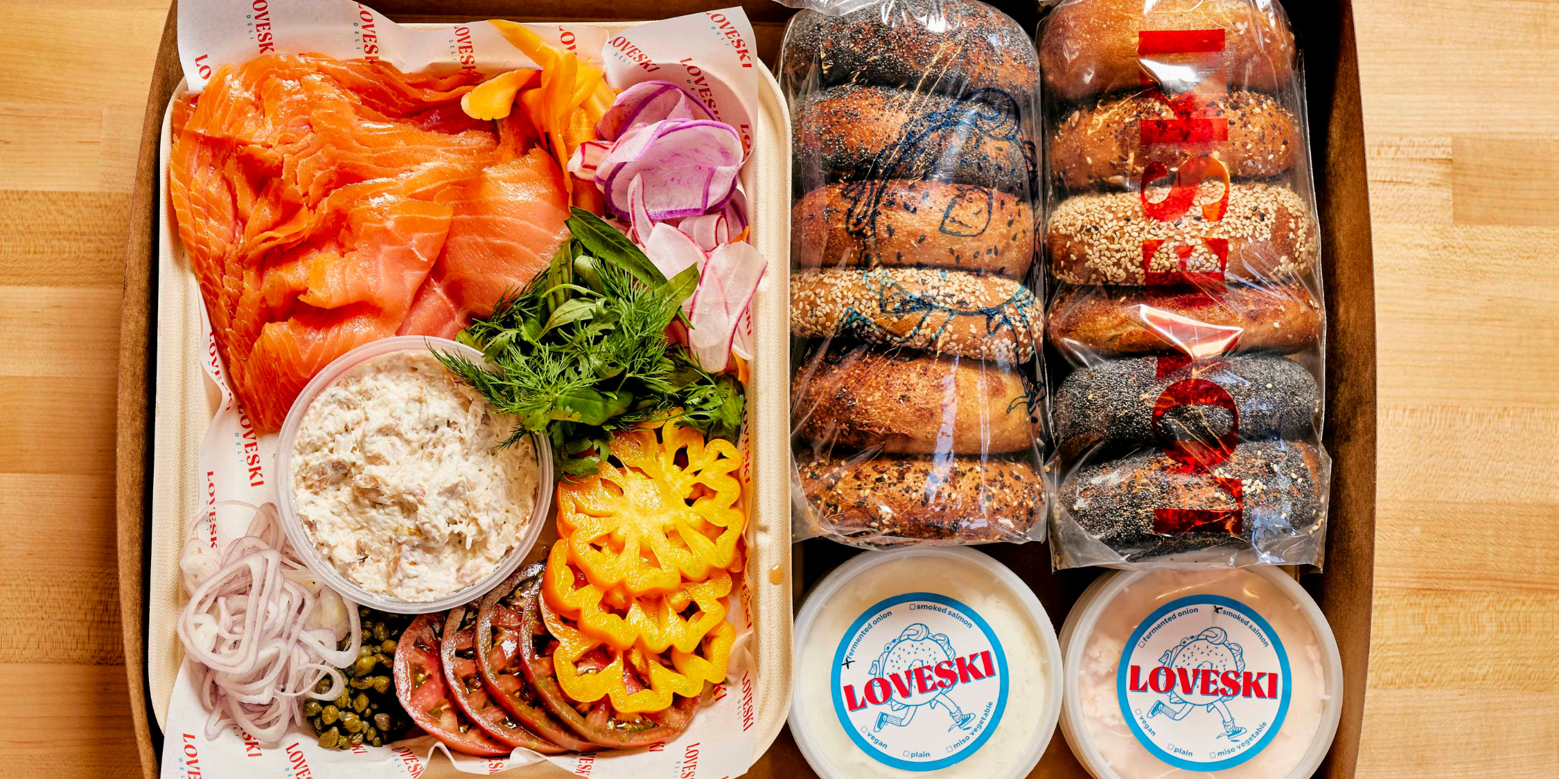 a box full of bagels, salmon, tomatoes, spreads