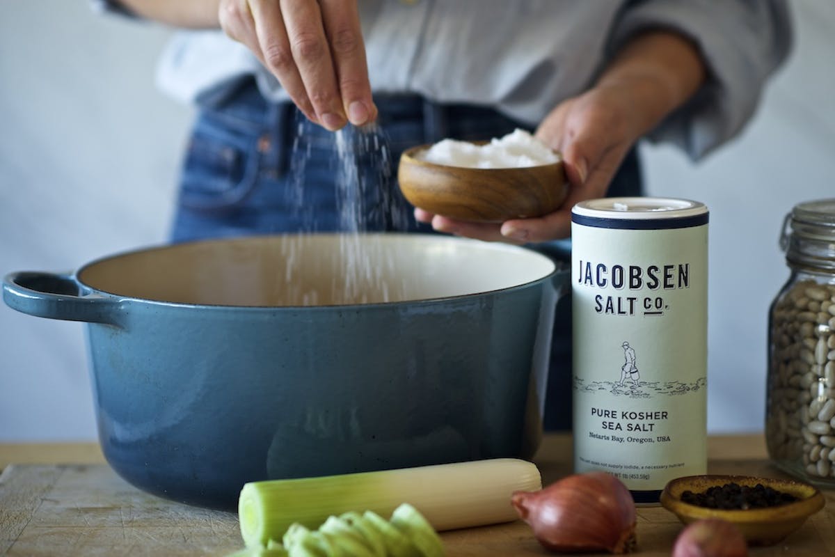 person sprinkling jacobsen salt into a crock pot