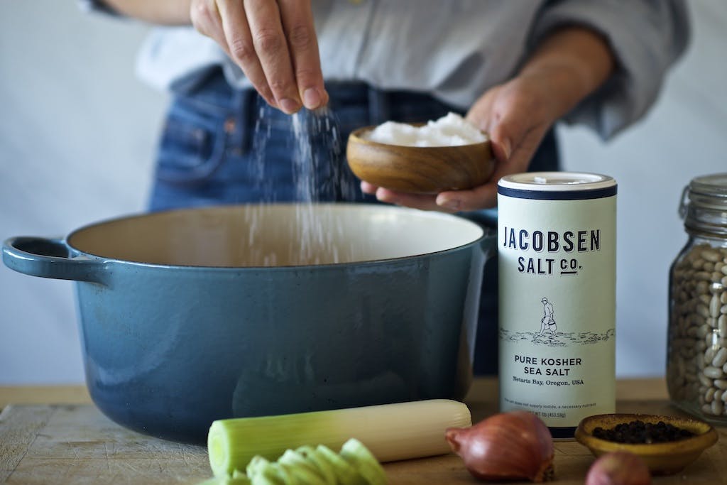 person sprinkling jacobsen salt into a crock pot