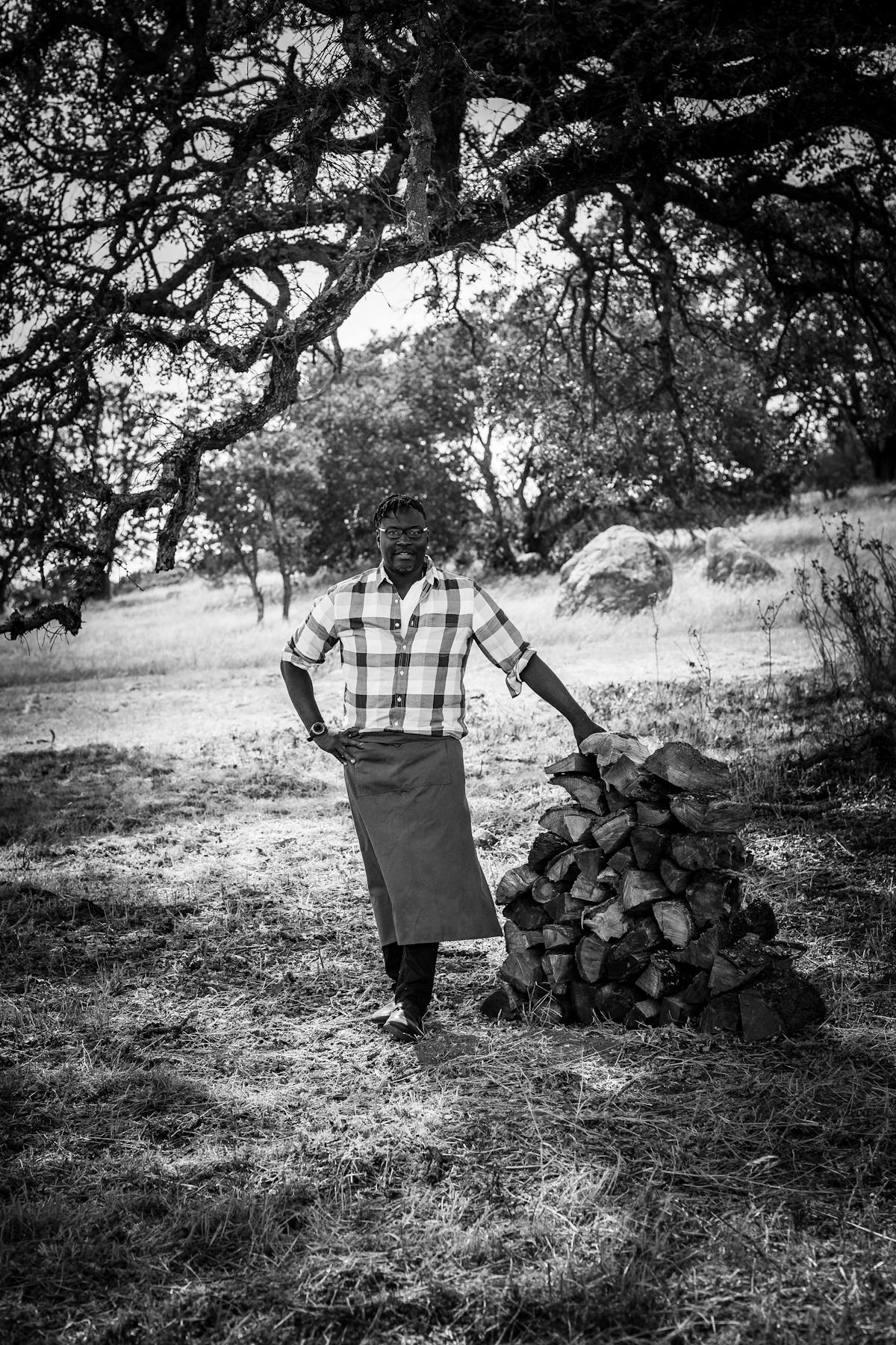 darryl bell of stateline road bbq next to a pile of logs