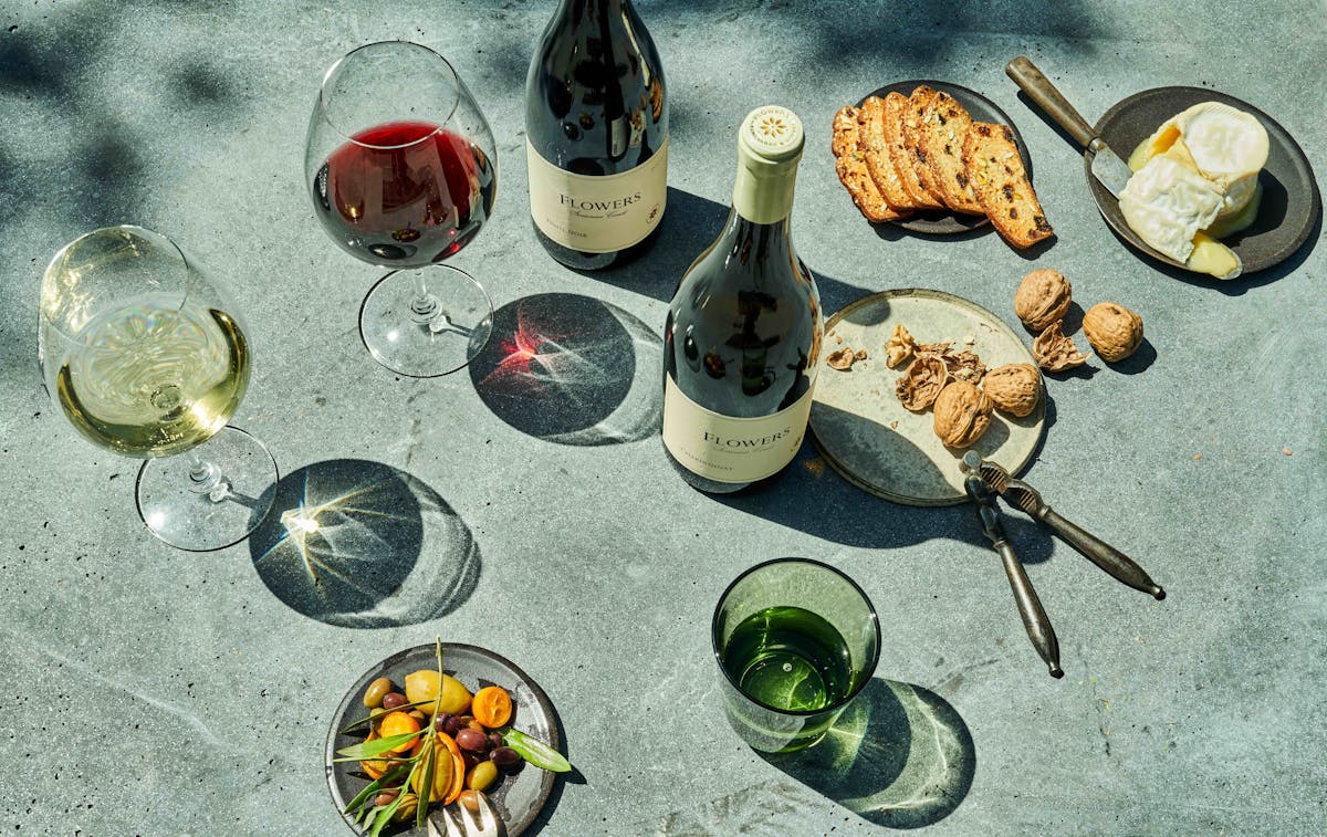 overhead shot of flowers wine bottles next to charcuterie