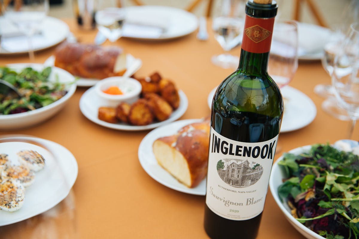 bottle of ingelnook wine in front of plates of loveski deli food