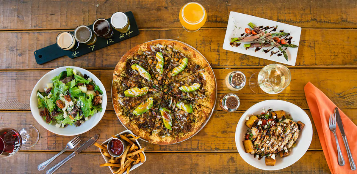 an overview of a table filled with a pizza and other plates of food