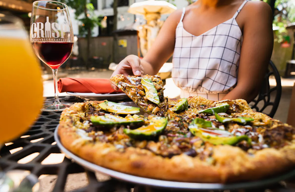 a person sitting in front of a table filled with a pizza and a bottle of wine