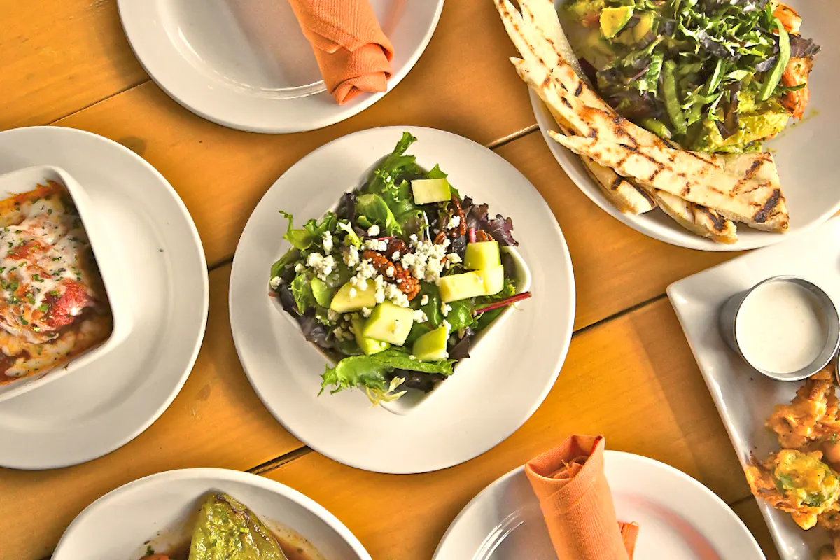 an overview of a table filled with multiple plates of food