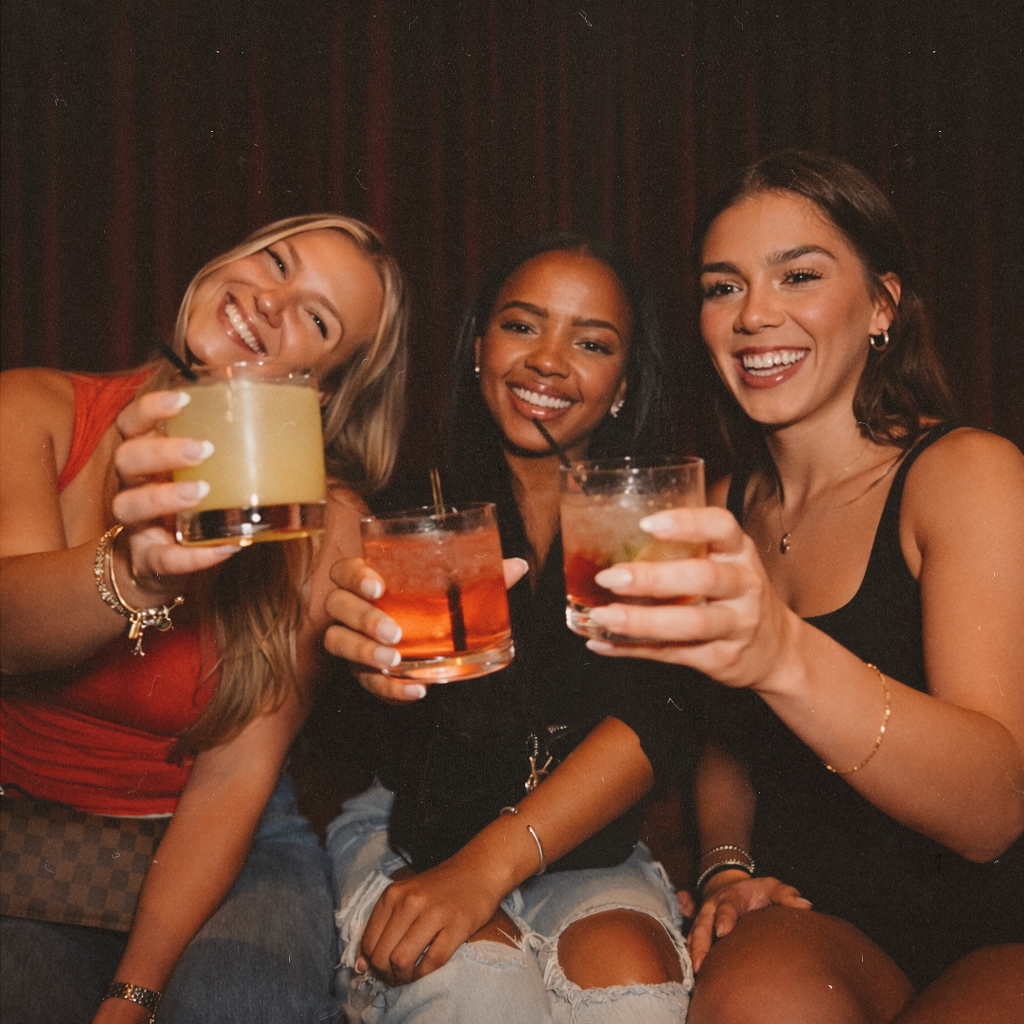 Three friends toasting craft cocktails at Wax Rabbit, a stylish Las Vegas speakeasy and cool bar known for vinyl music, live DJs, and girls’ night celebrations.