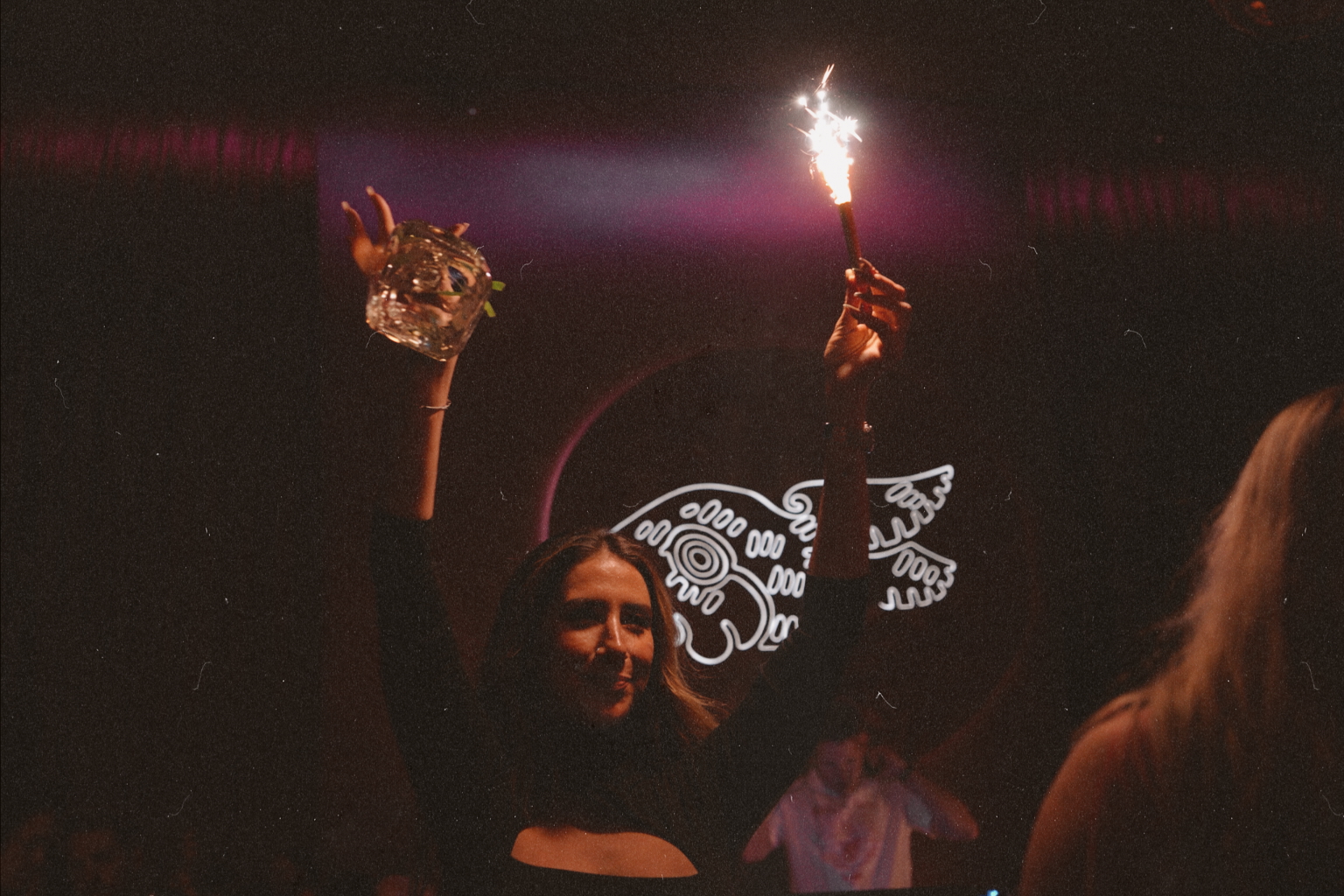 Guest holding a cocktail and sparkler inside Wax Rabbit speakeasy at Durango Casino & Resort in Las Vegas, featuring moody lighting and all-vinyl DJ nightlife atmosphere.