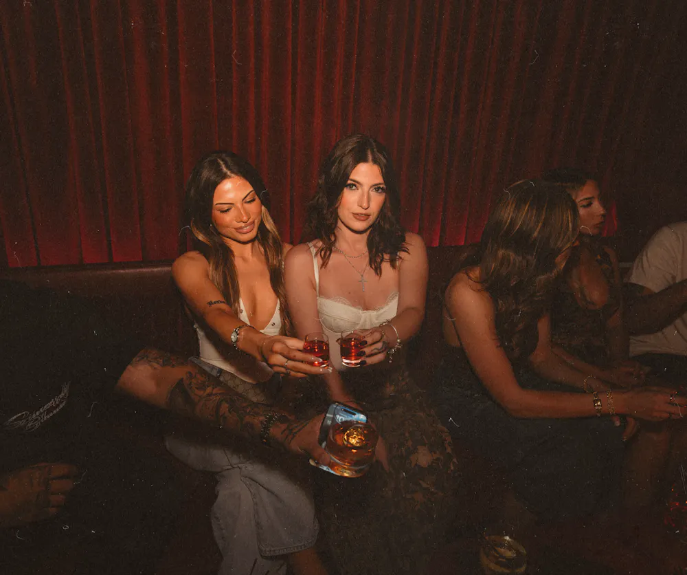 Friends enjoying handcrafted cocktails in a velvet booth at Wax Rabbit, a popular Las Vegas speakeasy and local lounge known for nightlife and vinyl music.