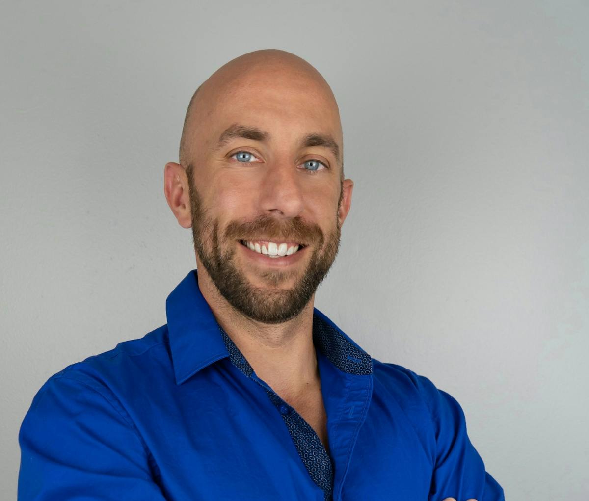 a man wearing a blue shirt and smiling at the camera