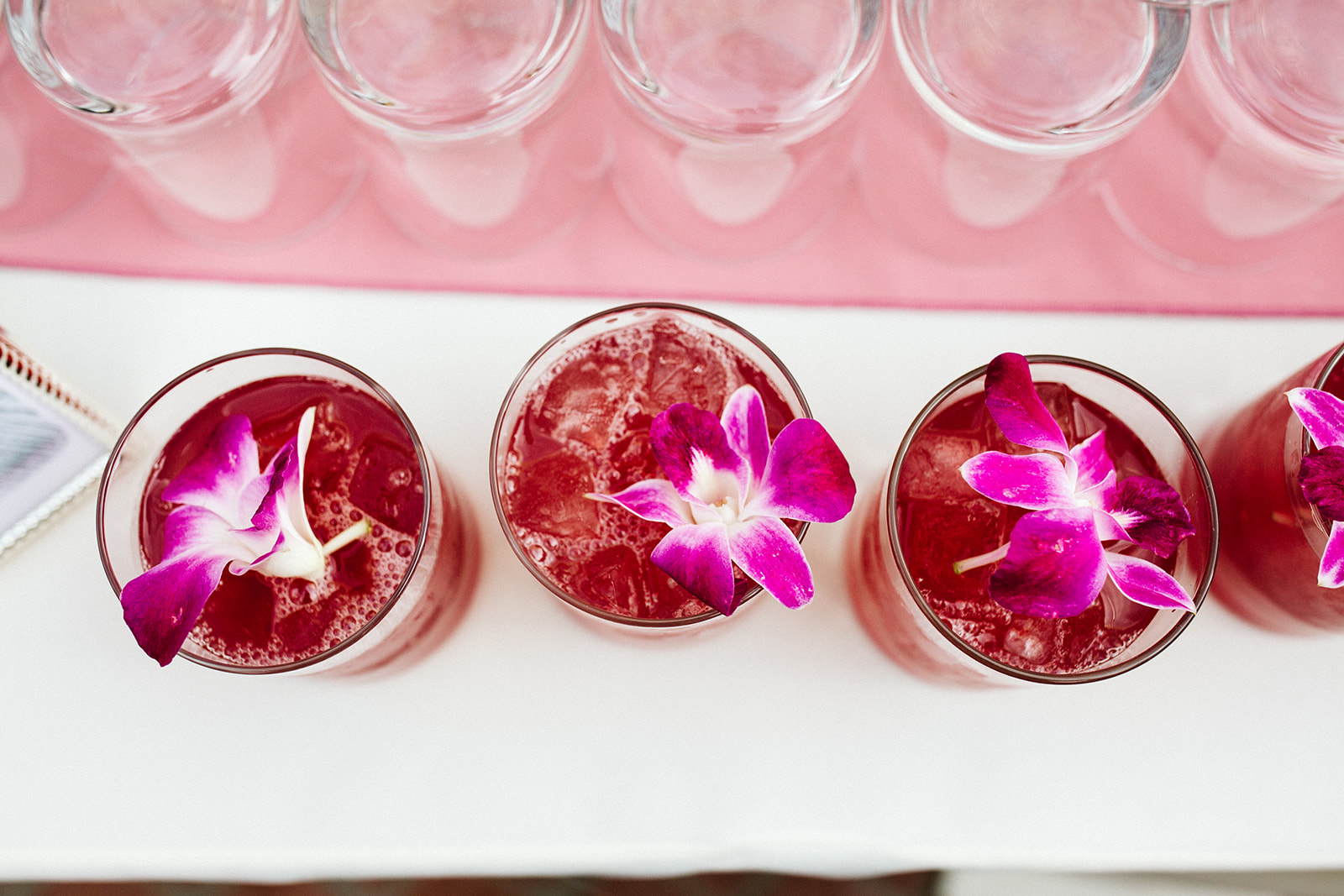 a row of glasses with red liquid and flowers on them