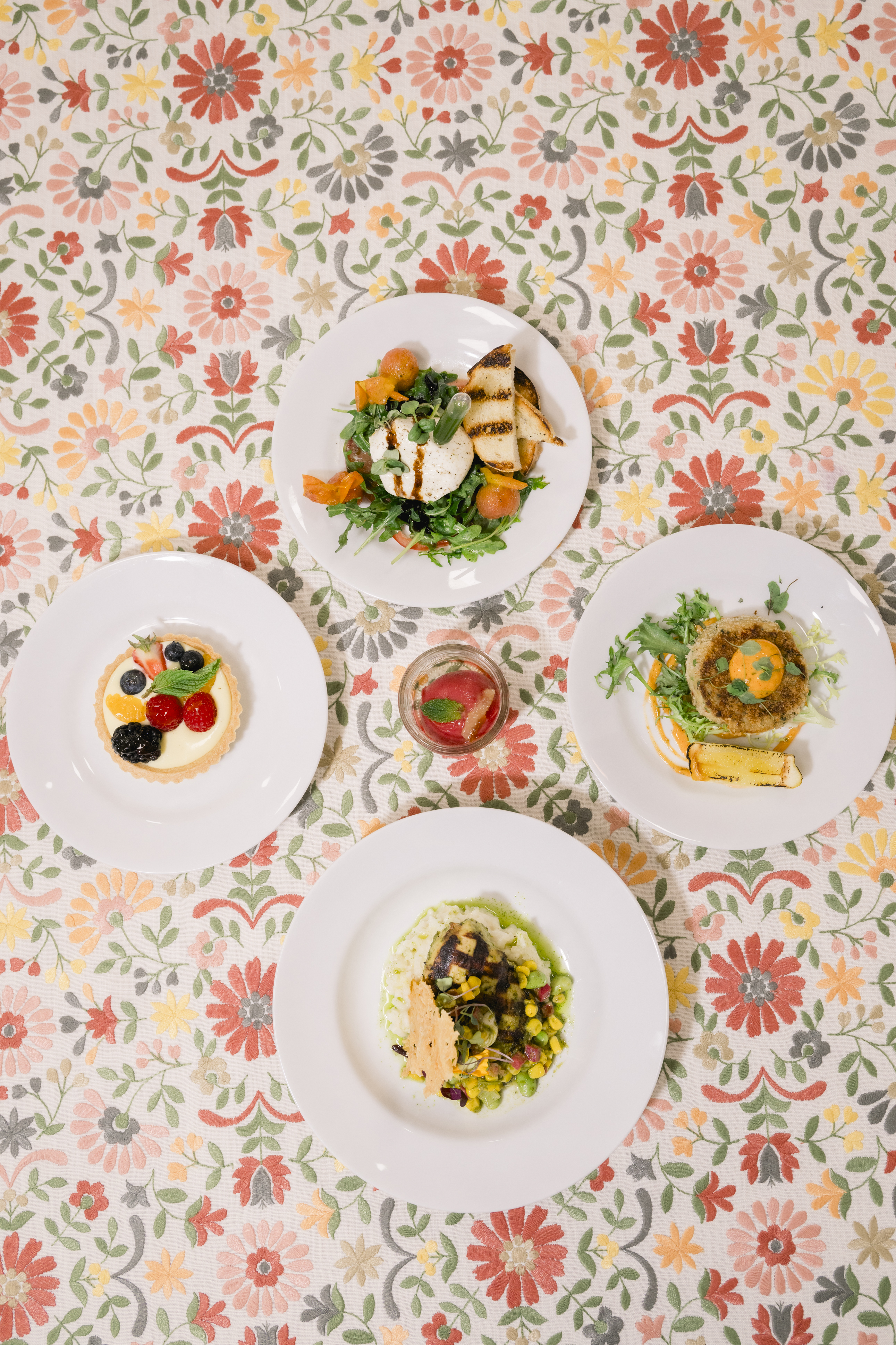 a group of plates of food on a floral tablecloth