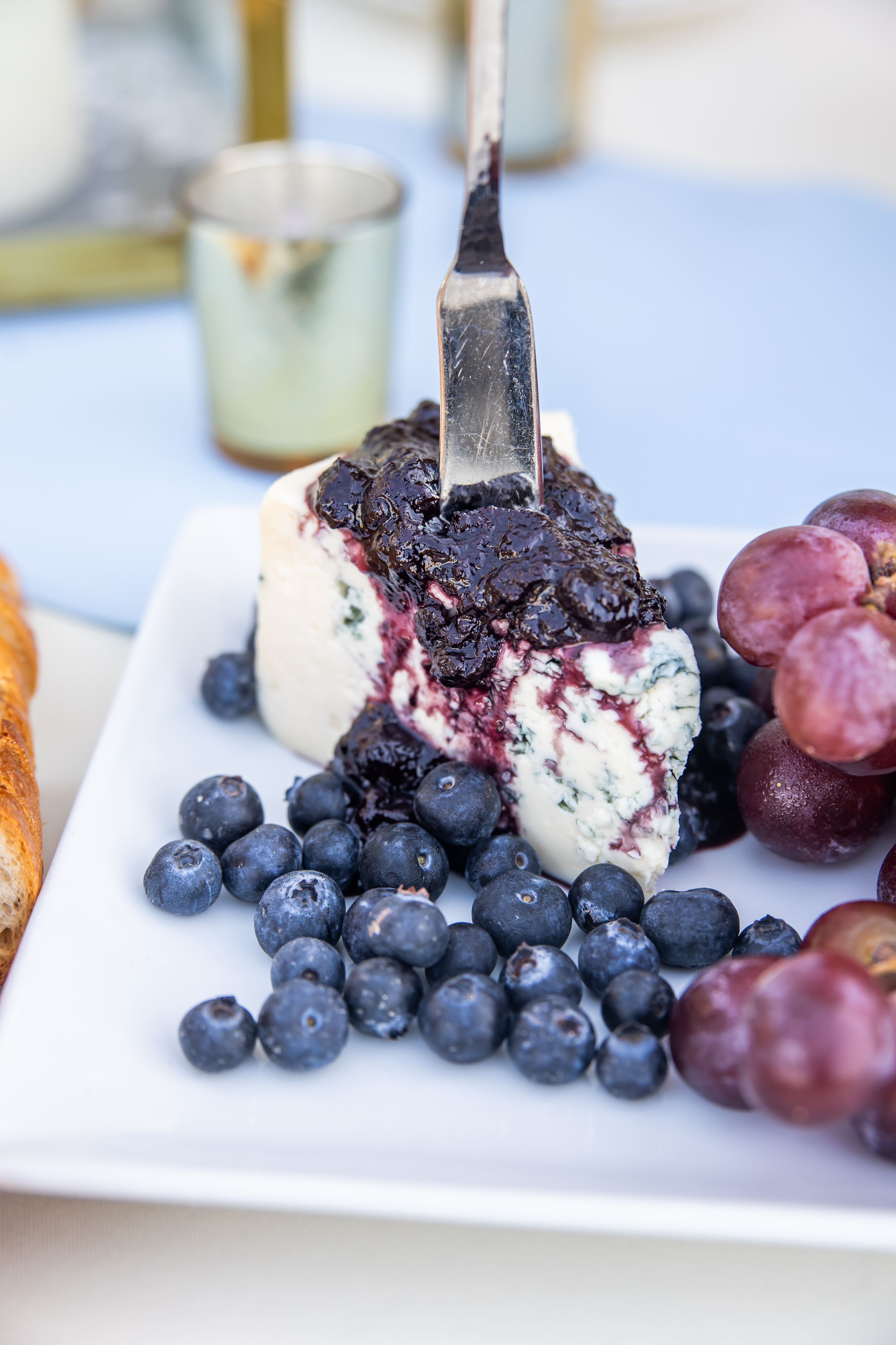 a piece of cheesecake with blueberries and grapes on a plate