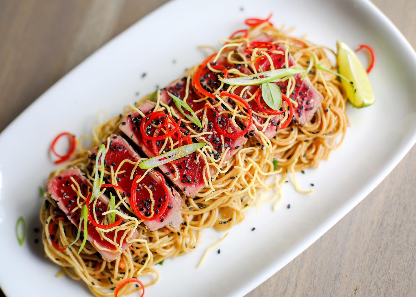 a plate with pasta and red meat and vegetables on top