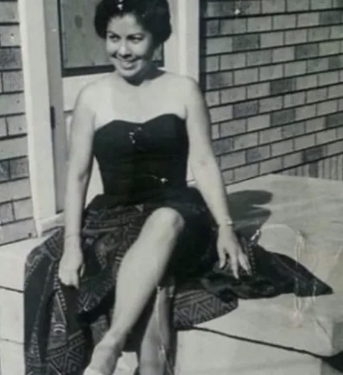 a woman sitting on a bench posing for the camera