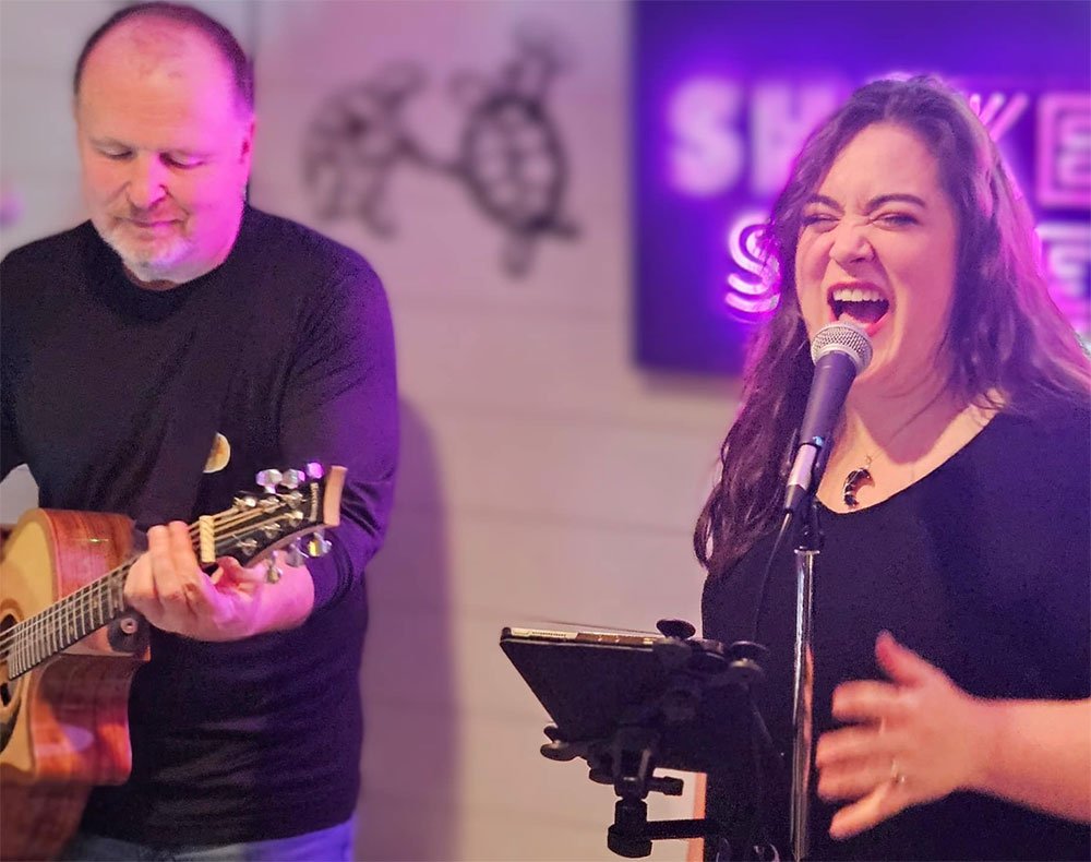a man and woman singing and playing guitar