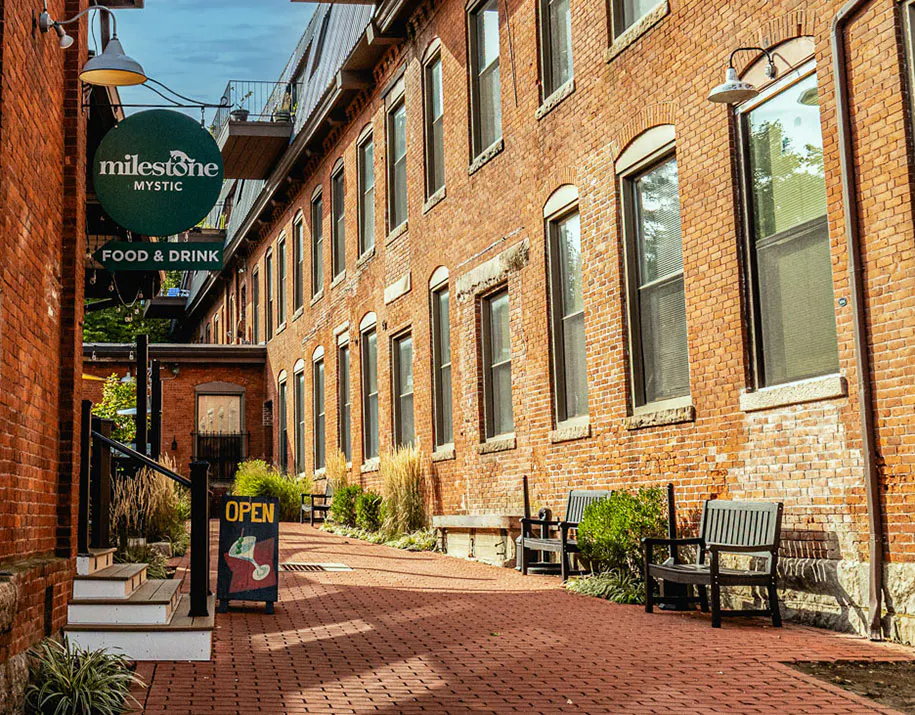 a brick walkway with benches and a sign