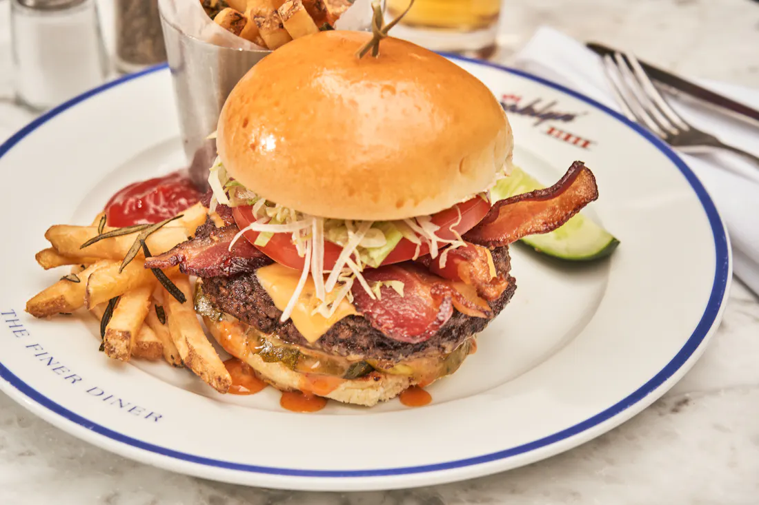 A bacon cheeseburger stacked high with a cup of hand-cut fries