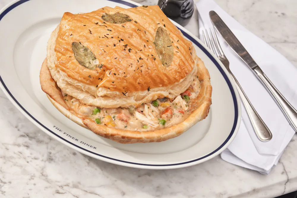 Chicken pot pie under a golden puff-pastry dome with sage