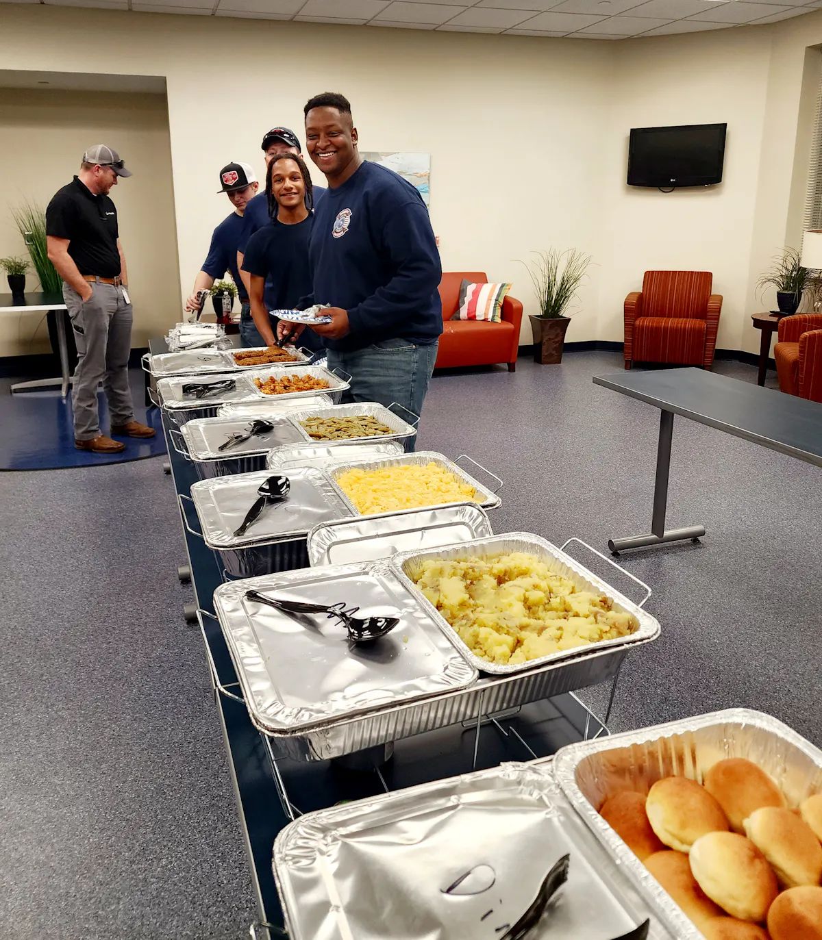 a group of people standing around a table with food