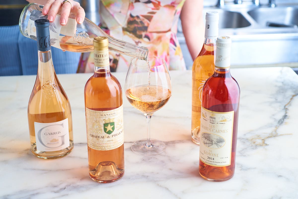 four bottles of rose on a table with a glass pour