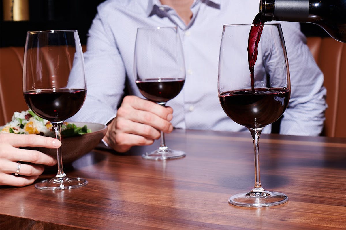 a person sitting at a table with wine glasses