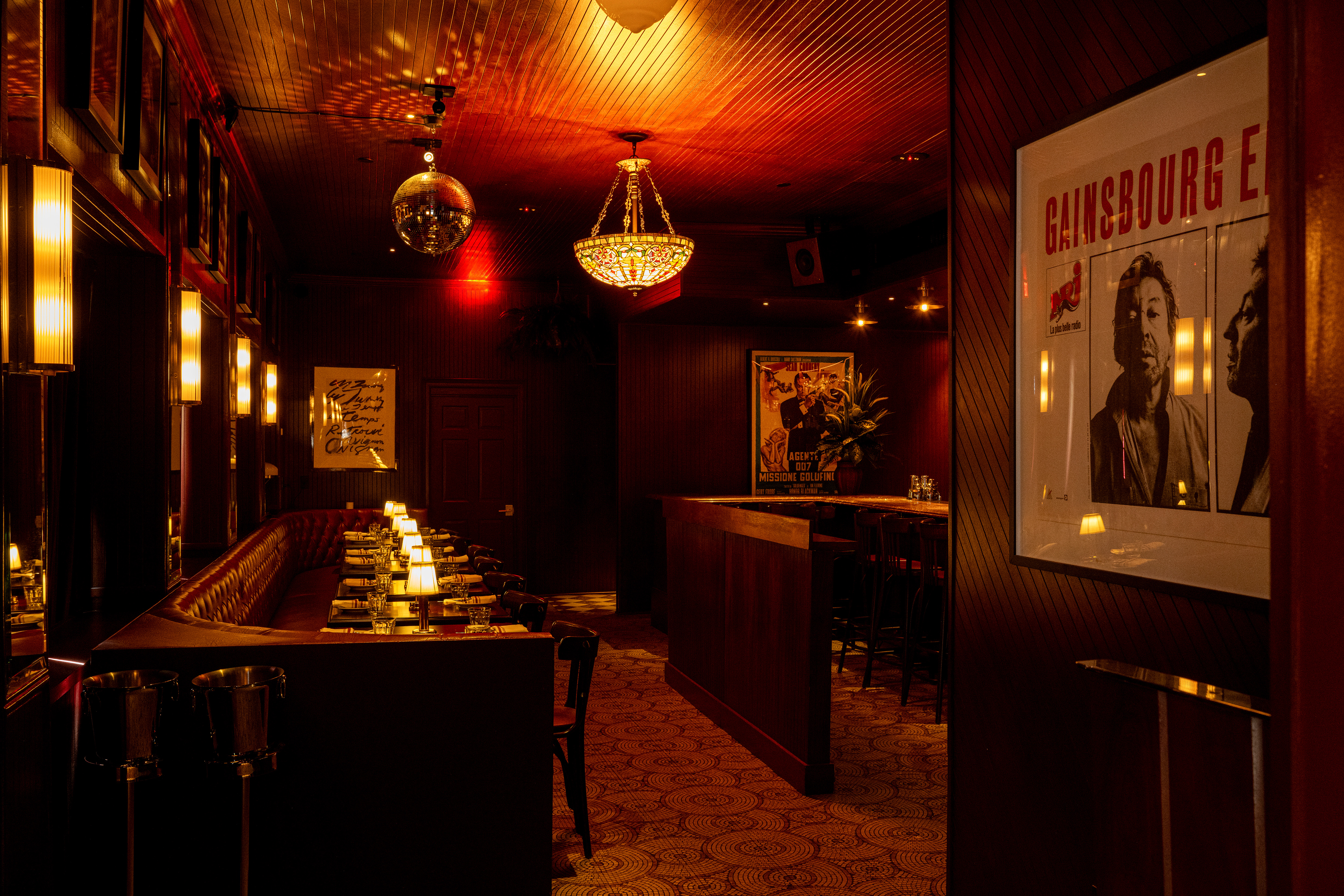 a room with a long booth and tables with candles