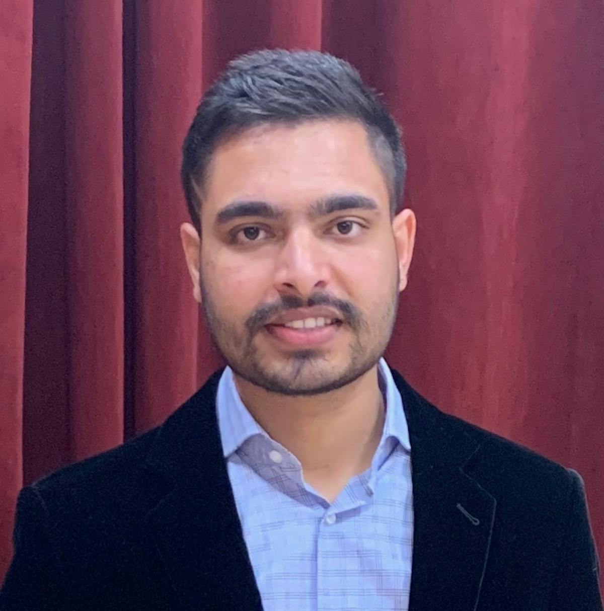 a man wearing a suit and tie smiling at the camera