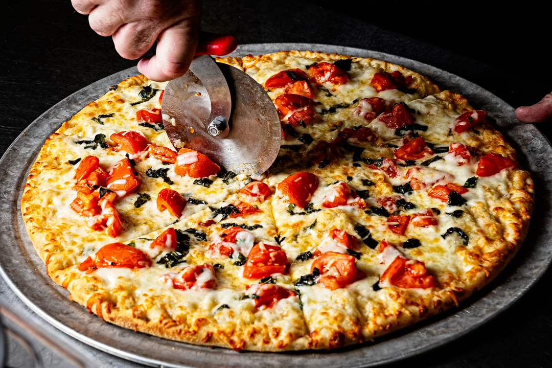 a pizza being sliced on a metal pan