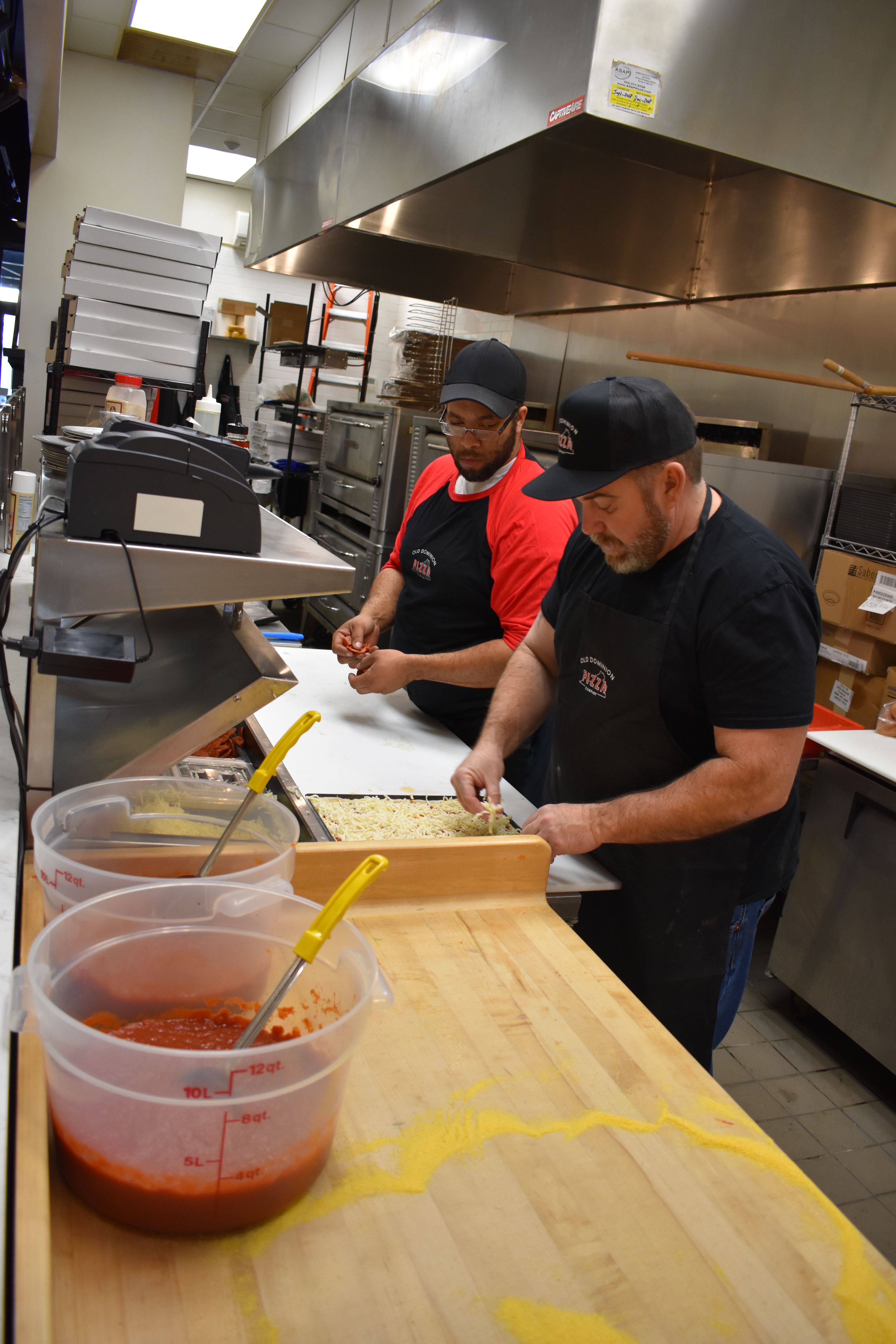 owners John Rodas and Charles Smith preparing pizza in the Old Dominion Pizza Company kitchen