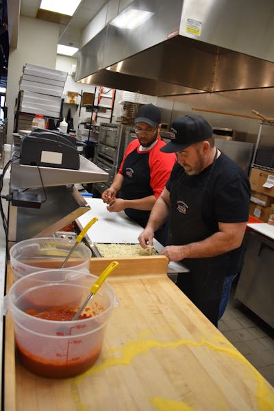 owners John Rodas and Charles Smith preparing pizza in the Old Dominion Pizza Company kitchen