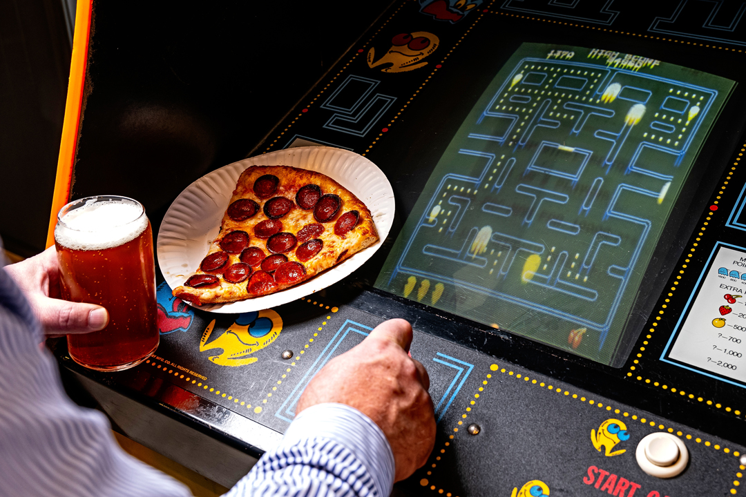 hot pizza and cold beer next to a classic arcade game