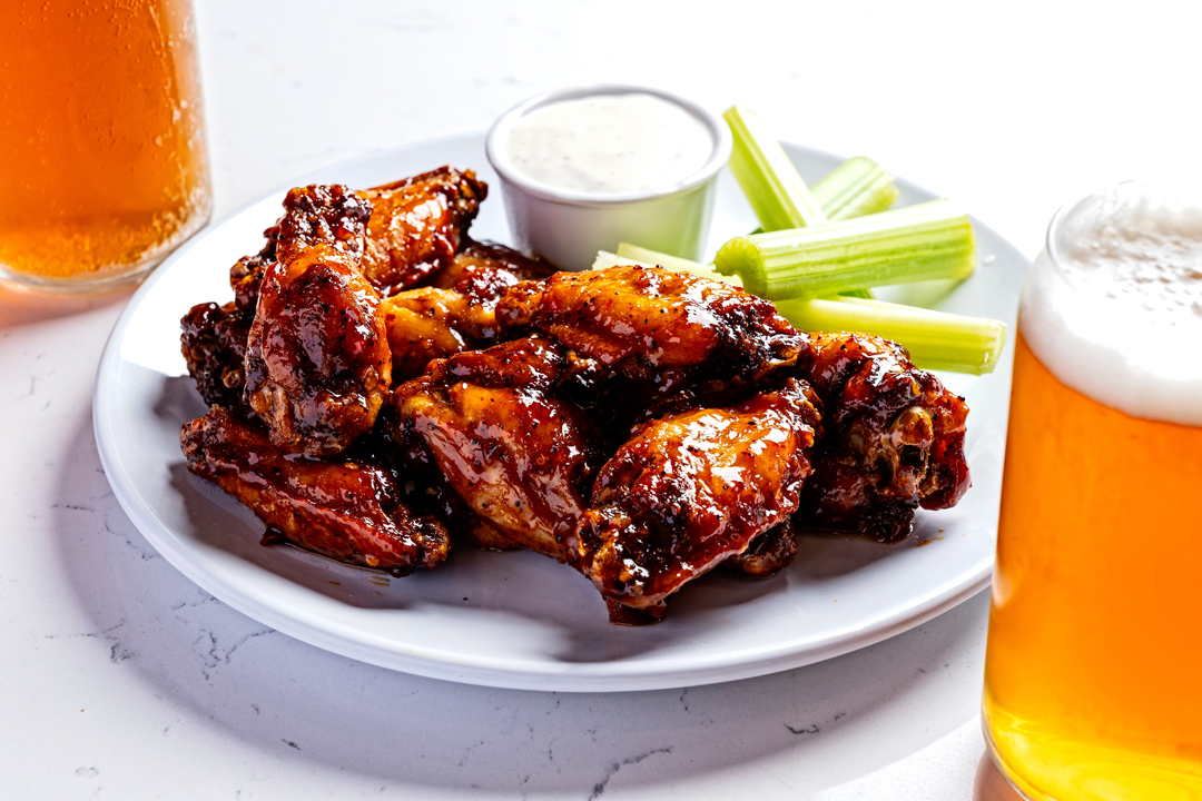 a plate of crispy buffalo wings with dipping sauce and celery