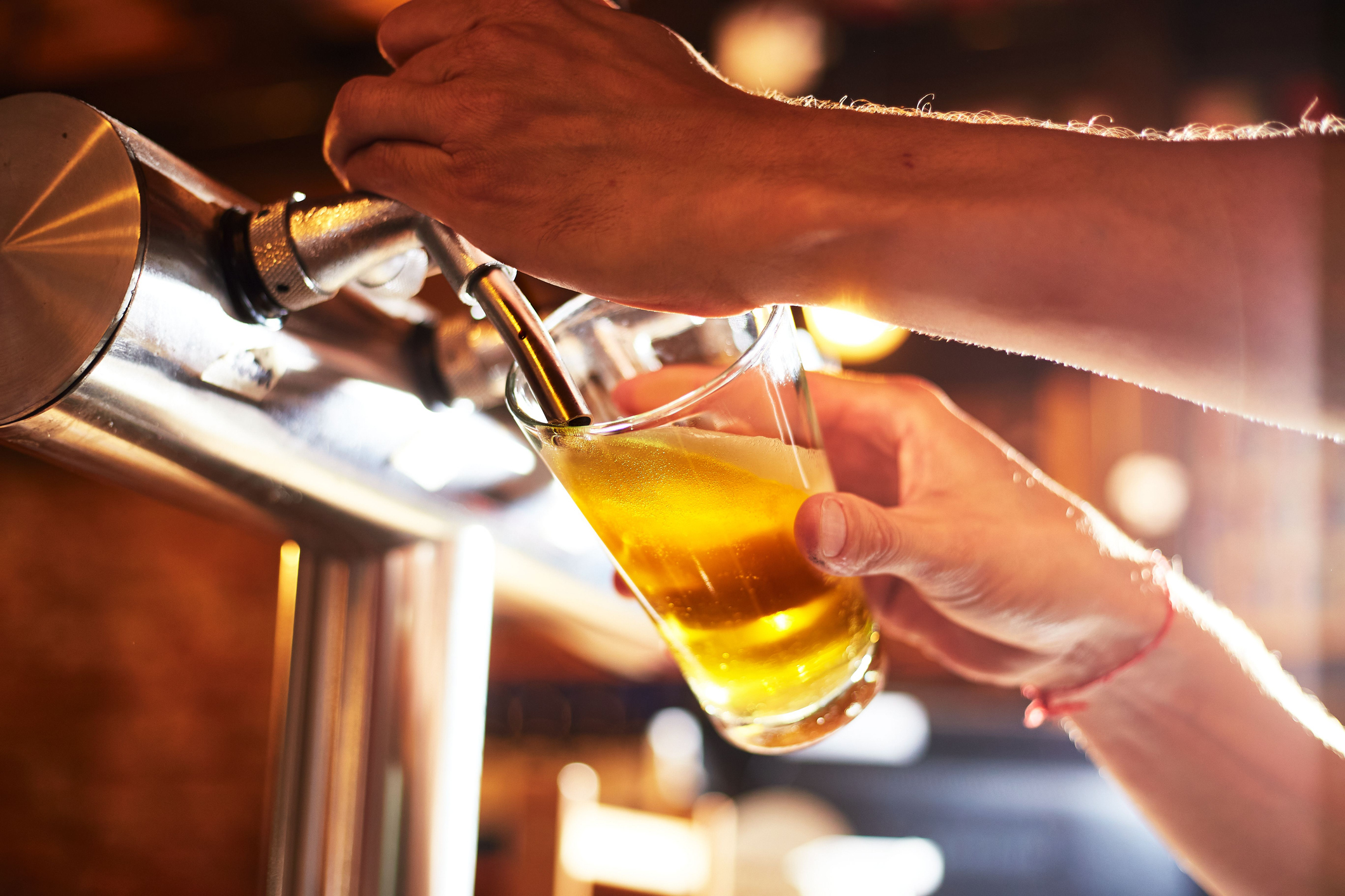 a hand holding a glass of beer on a table