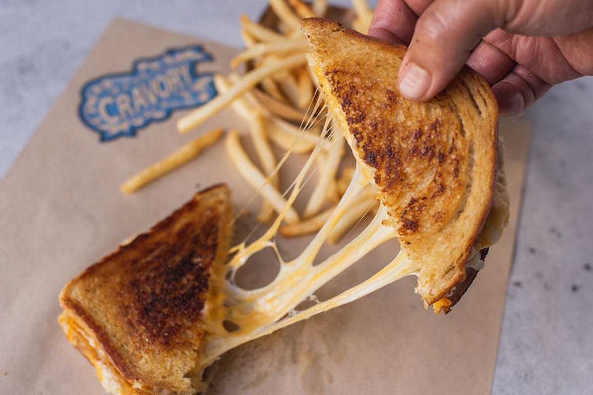 a hand holding a half eaten sandwich on a cutting board