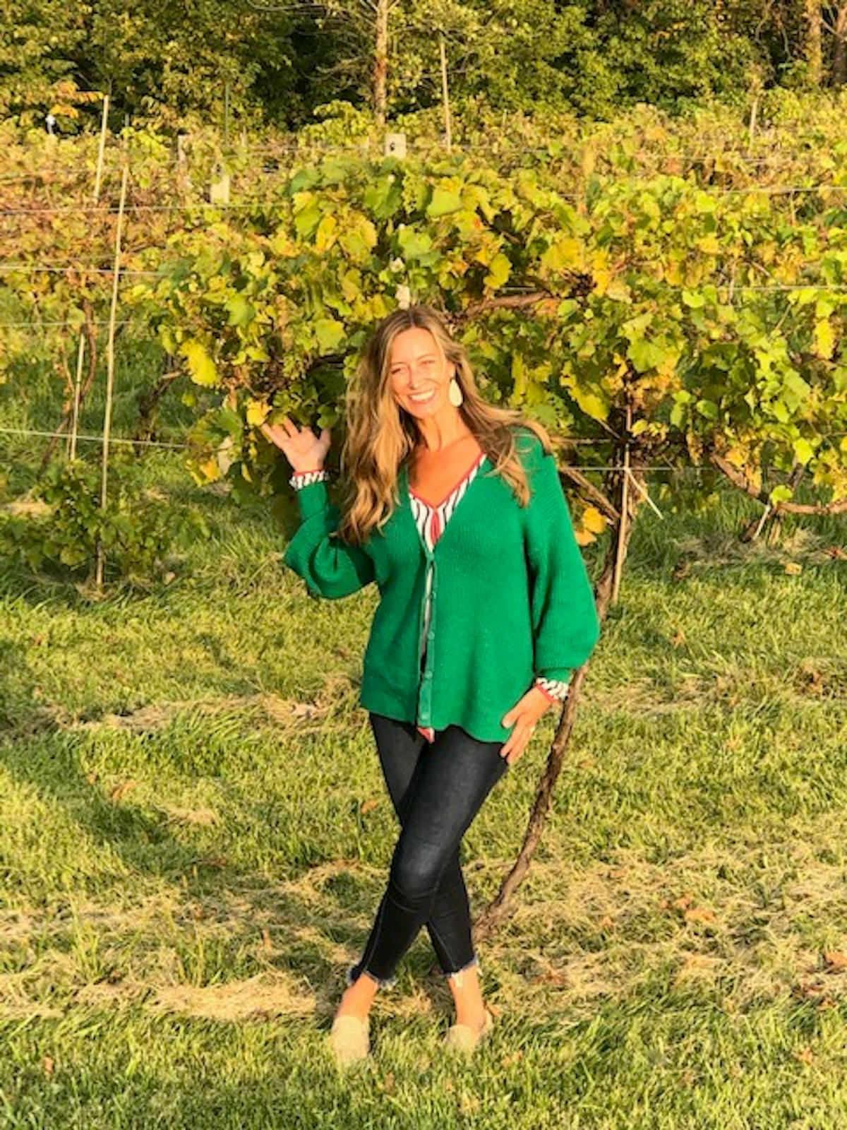 a woman in a green field with trees in the background