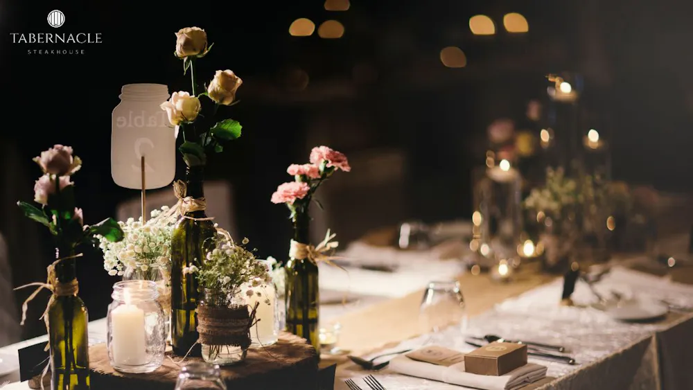 Floral centerpiece with candles and wine bottles at a kosher rehearsal dinner table in Manhattan at Tabernacle Steakhouse