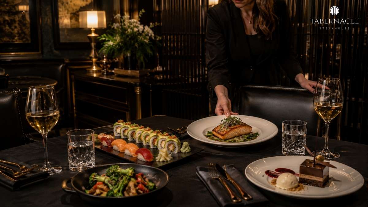 Server setting a dinner table with salmon, sushi rolls, vegetables, and dessert