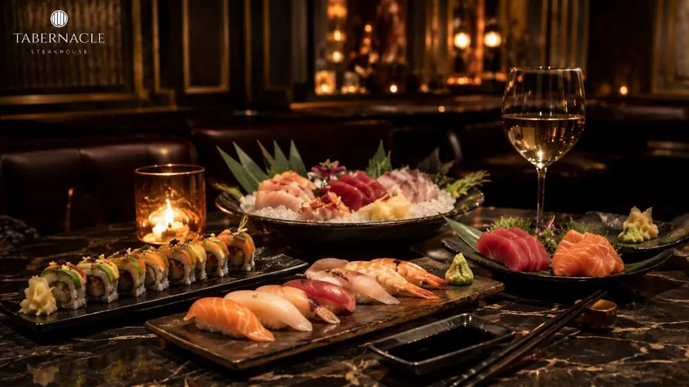Sushi rolls, nigiri, and sashimi platters with white wine in a candlelit dining room