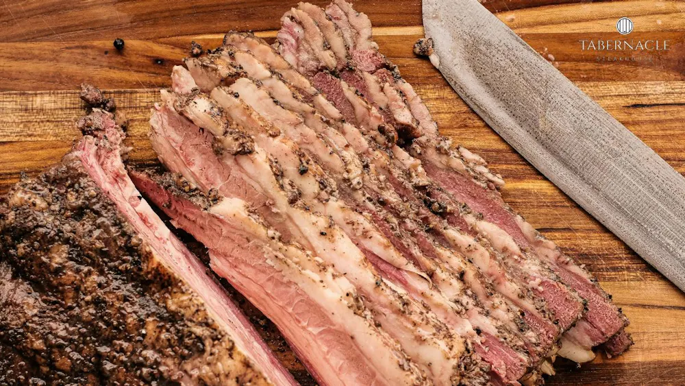 Thick-cut kosher short rib sliced on a wooden board at Tabernacle Steakhouse, Midtown Manhattan