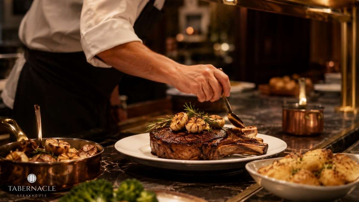 chef-plating-bone-in-ribeye-with-roasted-garlic-in-fine-dining-kitchen