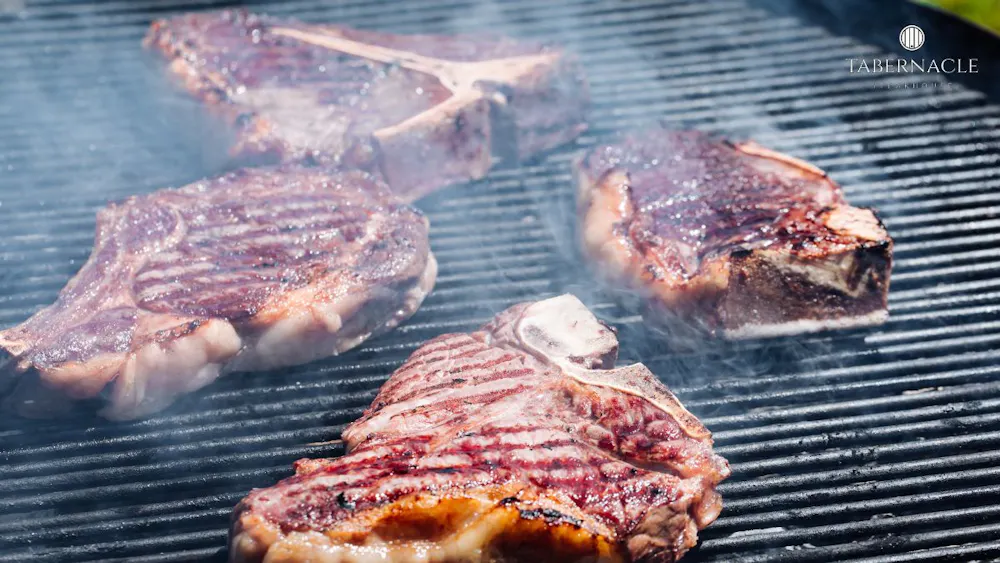 Wagyu and dry-aged steaks searing on the grill at Tabernacle Steakhouse, a kosher steakhouse in Midtown Manhattan