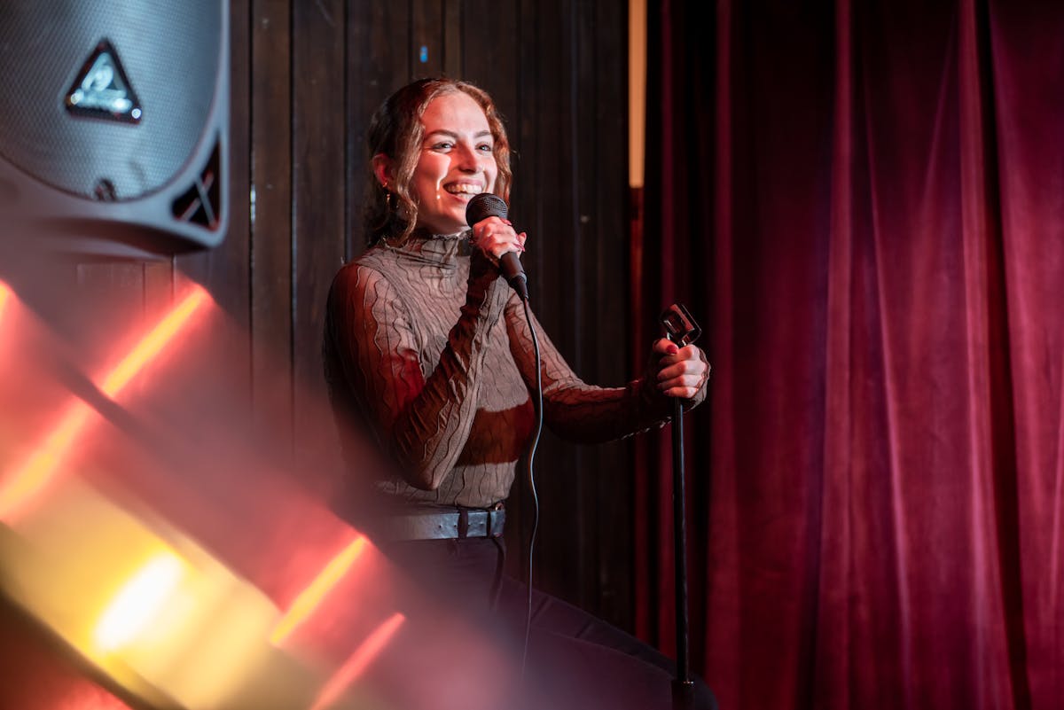 a person standing on a stage in front of a curtain