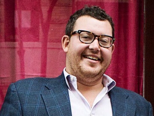 a man wearing glasses and smiling at the camera